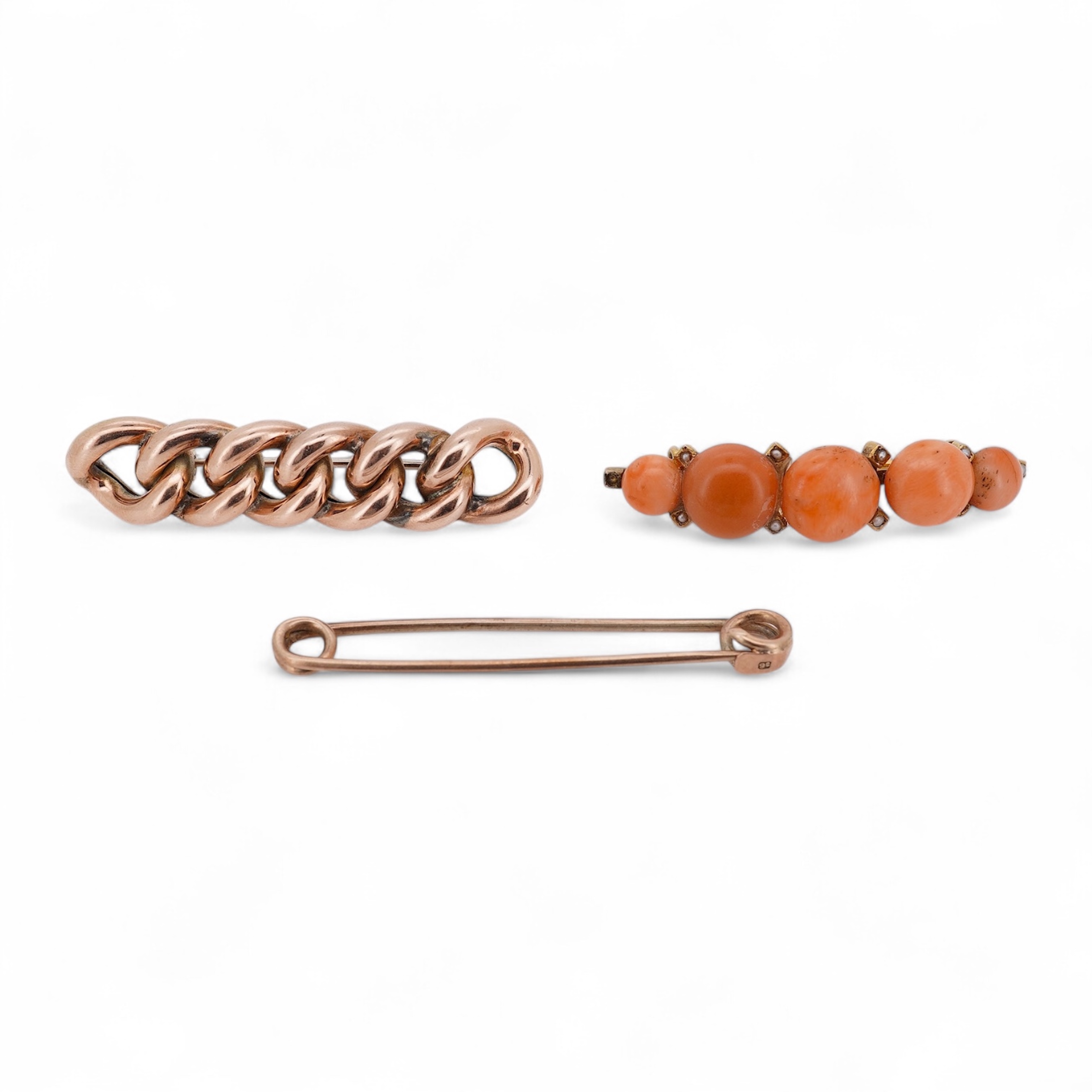 An early 20th century yellow metal and graduated five stone coral bead brooch, with seed pearl spacers, 45mm, together with a yellow metal curb link brooch and a yellow metal (stamped 9c) safety pin. Condition - fair
